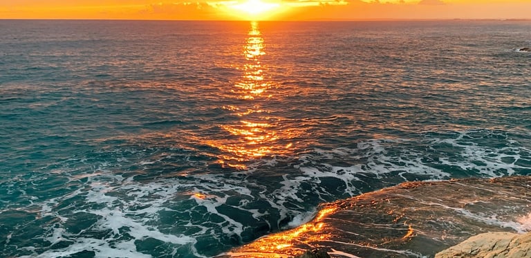 Golden Cyprus sunset with waves crashing against a rocky Mediterranean coastline.