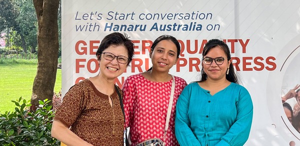 3 women in front of large placard