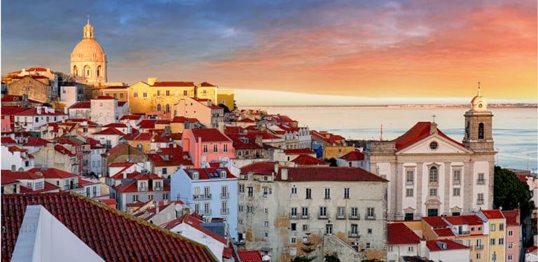 Panoramic sunset over Lisbon's Alfama district featuring red tile roofs and the National Pantheon.