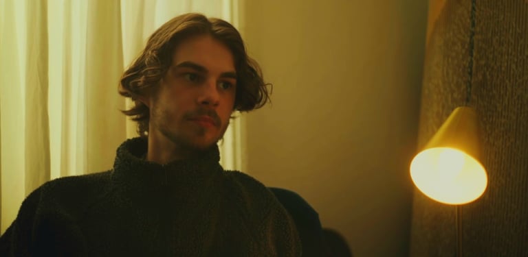 a man in a black sweater and a light bulb on a lamp