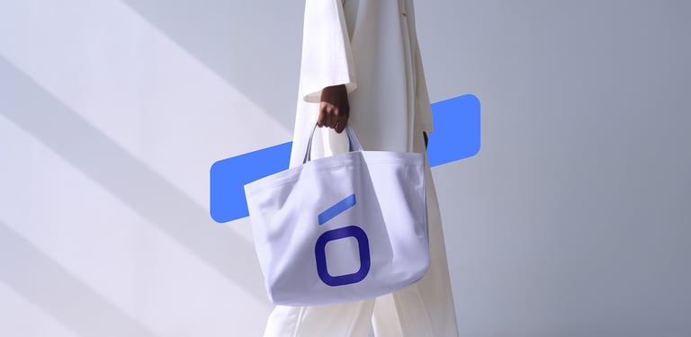 A person in white clothing carrying a large white branded tote bag with a blue logo.