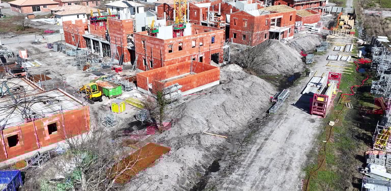 Vue aérienne d'un chantier résidentiel avec des maisons en brique rouge des échafaudages et une grue