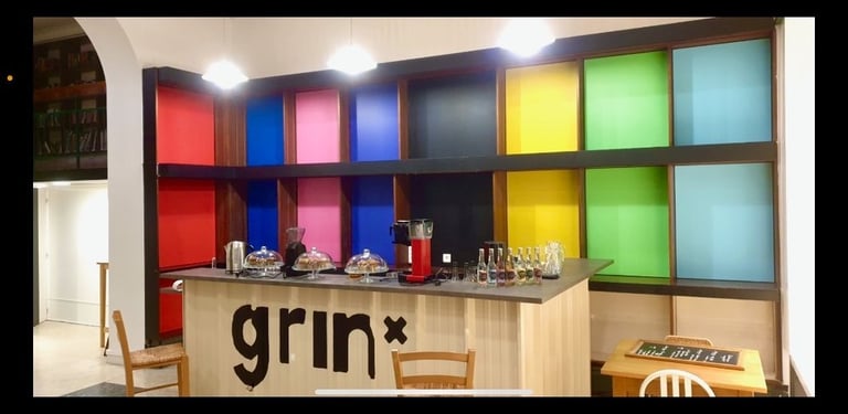 un bar avec une fresque avec des triangles de couleurs vives et des inscriptions noir et blanches