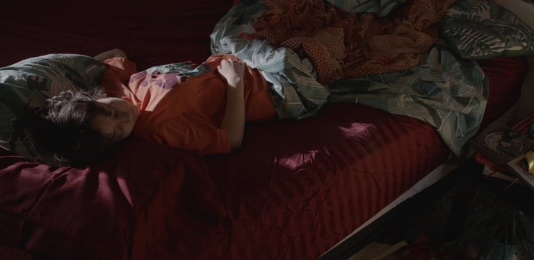 a woman laying on a bed with a blanket