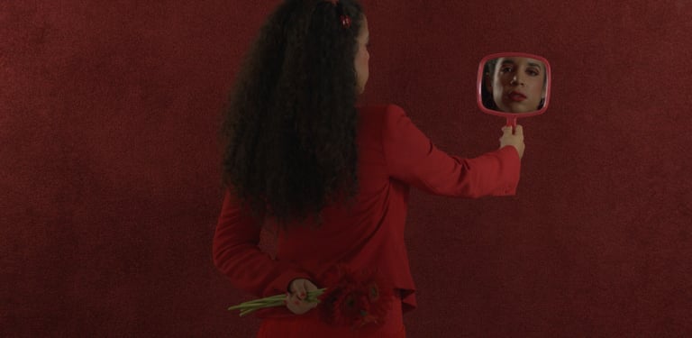 a woman in a red dress is holding a mirror