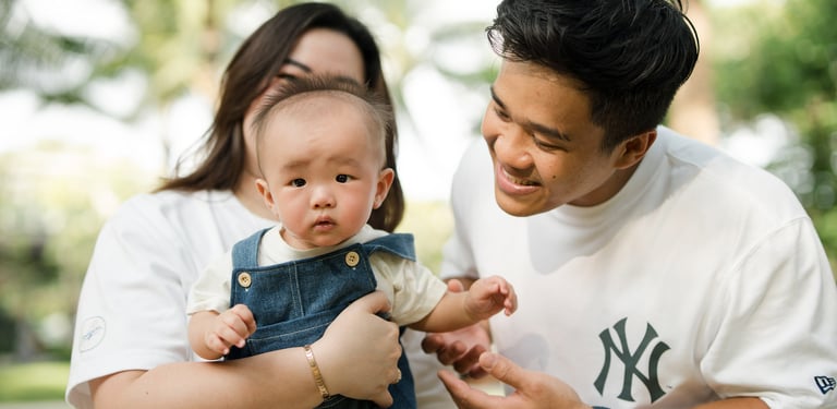 Parents holding their baby during a relaxed family photography session at The Apurva Kempinski Nusa Dua Bali