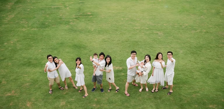 Multigeneration family photography session at Alila Seminyak Bali with family members walking together on green lawn.