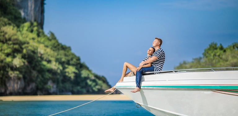 A couple sitting at the edge of a white speedboat, enjoying the sun during their honeymoon on Samui