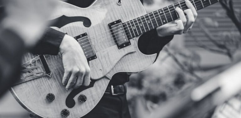 a black and white photo of a man playing guitar 