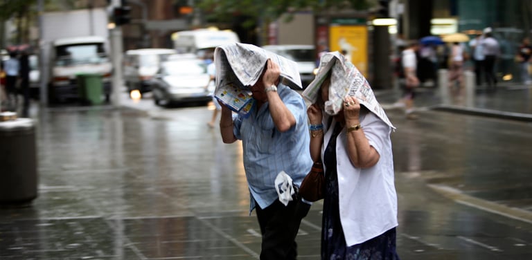 two people with newspapers over their heads in the rain