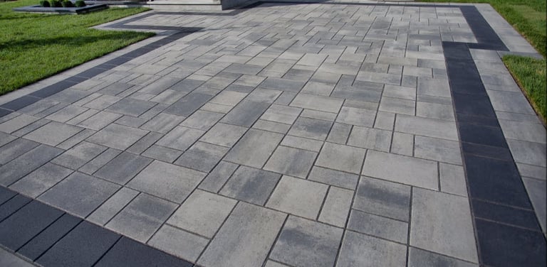 a driveway with light and dark pavers, and a dark border all around