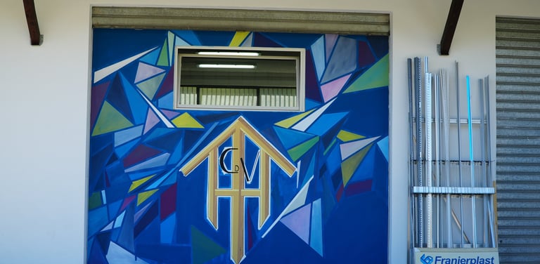 A colorful geometric blue mural painted on an exterior wall at the Franjerplast facility.