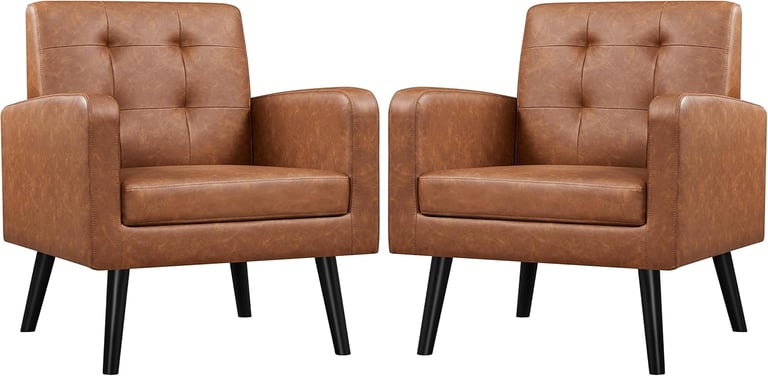 Pair of cognac brown faux leather accent chairs with tufted backrests and black tapered legs.