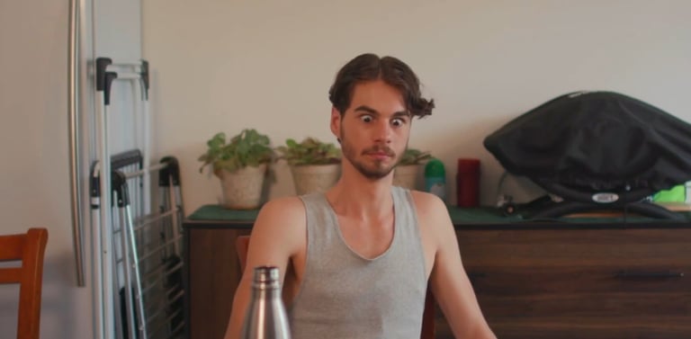 a man sitting at a table with a bottle of beer
