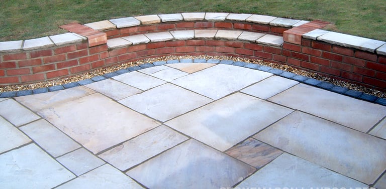 Multi-level sunken sandstone patio step up to lawn with retaining wall