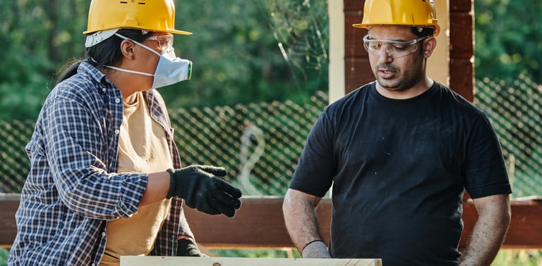 A man and woman in protective gear standing in front of a building