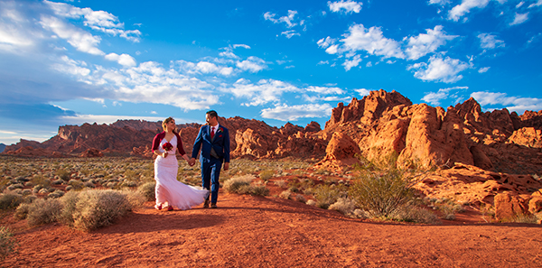 a bride and groom walking down a dirt road