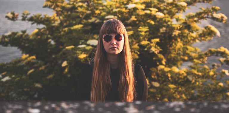 a woman with long hair and sunglasses in front of a brush