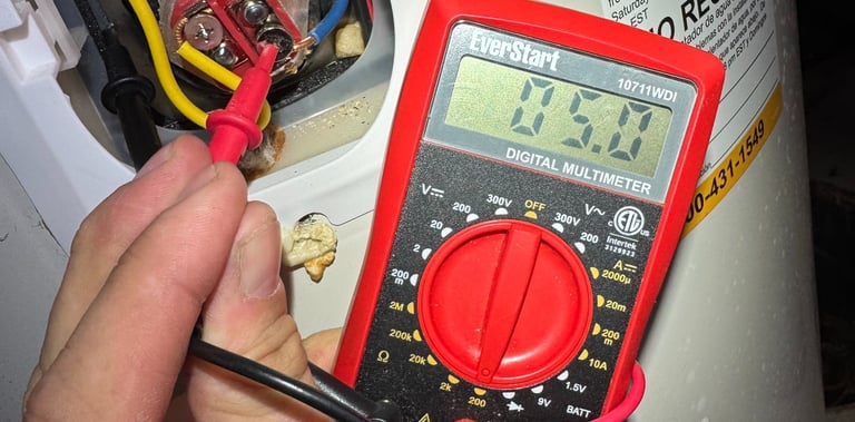 A technician uses a digital multimeter to test a water heater heating element for electrical continuity.