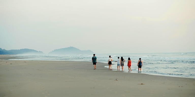 Group of friends walking together along a Greek beach at sunset