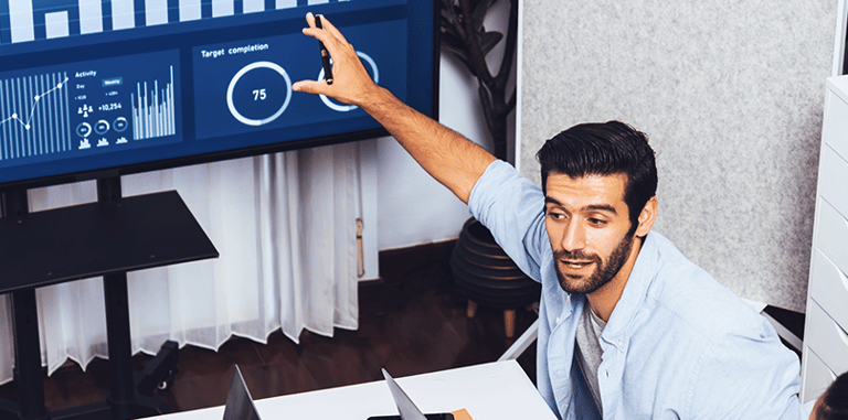 Professional businessman presenting data analytics and KPIs on a digital dashboard screen to his team.