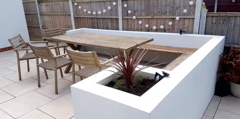 Modern chic raised porcelain patio with white rendered walls and planters