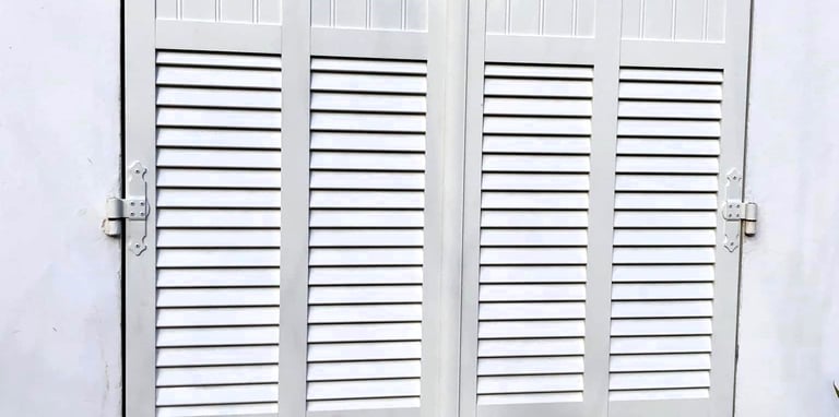 Volets battants blancs à persiennes.