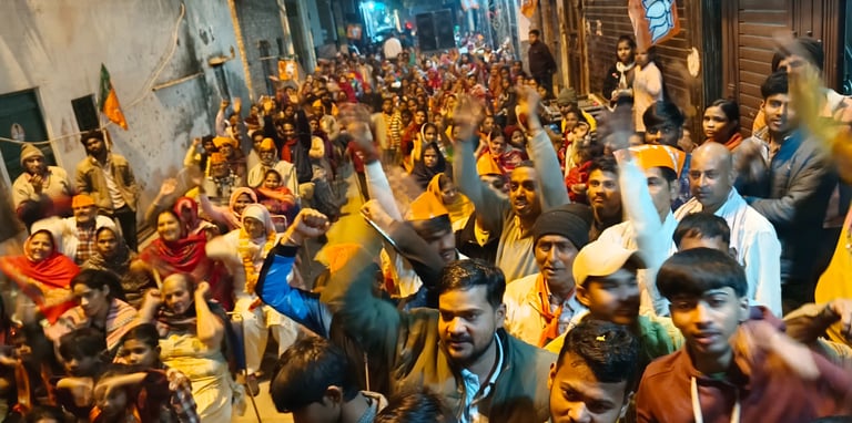 A large crowd of people gathered in a narrow street for a political rally in India with saffron flags.