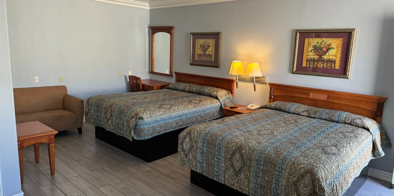 a motel room with two beds a lamp and a couch