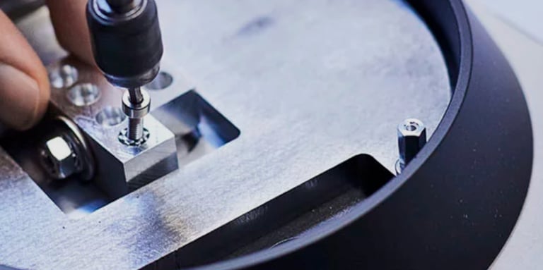 A technician using a precision tool to tighten a screw on an aluminum mechanical assembly.