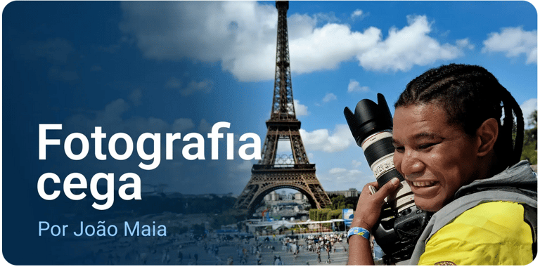 João segura uma câmera fotográfica profissional com uma lente acoplada. Ao fundo, a torre Eiffel.