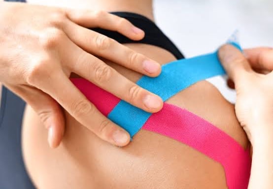 Physiotherapist apply tapping on shoulder jiont to reduced inflammation and pain.