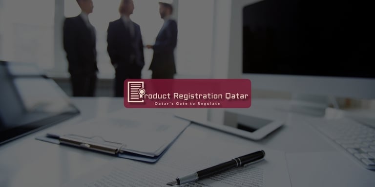 Business meeting scene with documents, pen, and computer, representing regulatory consulting services in Qatar.