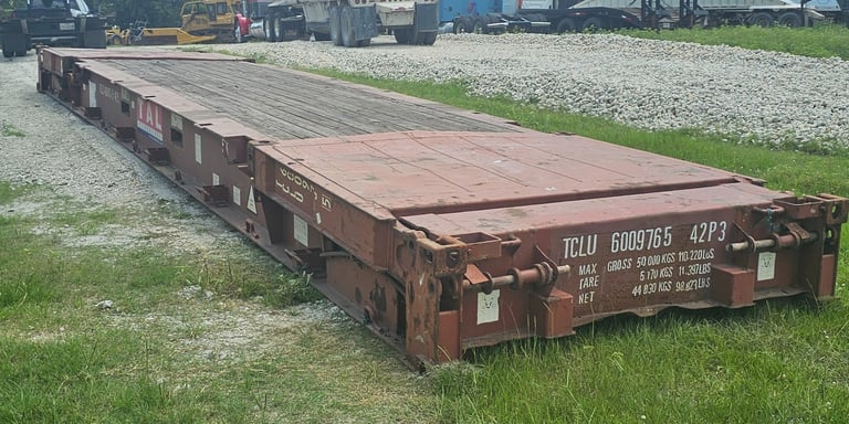 A red 40ft flat rack laying on the ground
