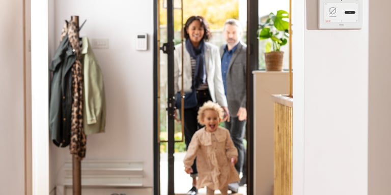 Family coming home with security panel on wall