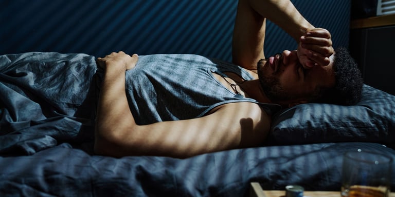 A man lying in bed suffering from overthinking and insomnia during the night.