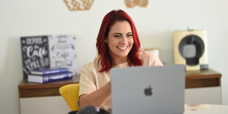 Psicóloga Palloma D'Andrade sorrindo, em frente ao computador explicando sobre psicoterapia online