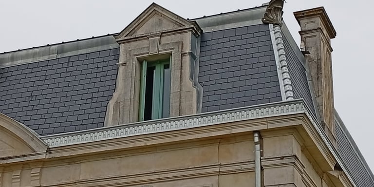 Architecture européenne historique avec un toit mansardé recouvert d'ardoises grises et une lucarne 