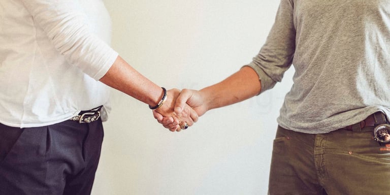 two men shaking hands with a woman in a white shirt