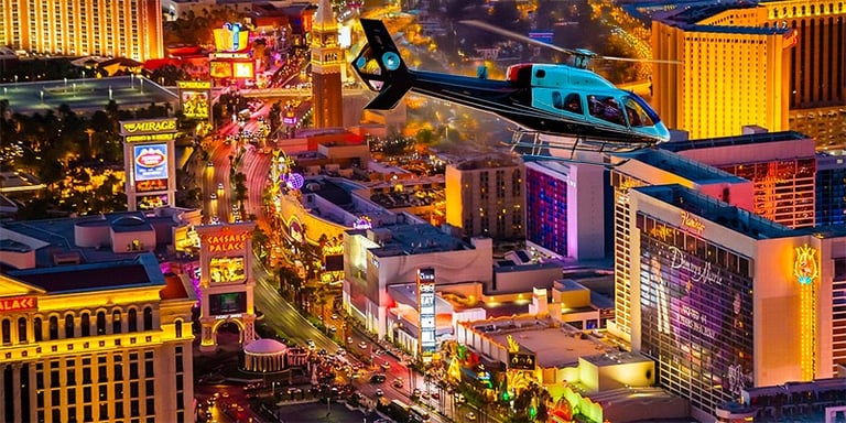 A scenic helicopter tour flying over the glowing neon lights of the Las Vegas Strip at night.