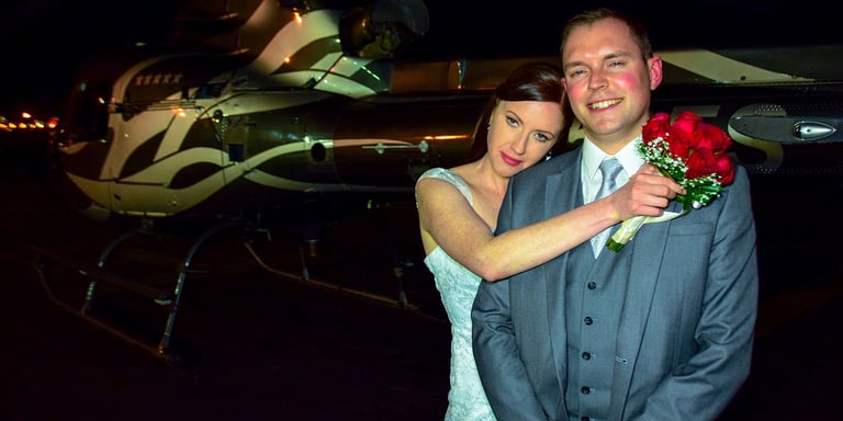 a man and woman standing in front of a helicopter