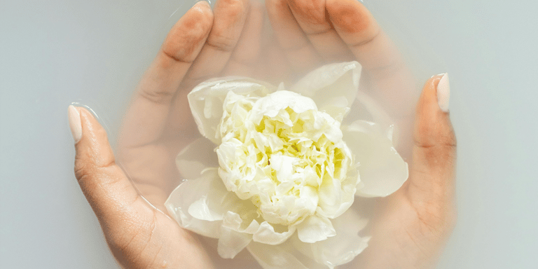 a person holding a flower in their hands with manicure