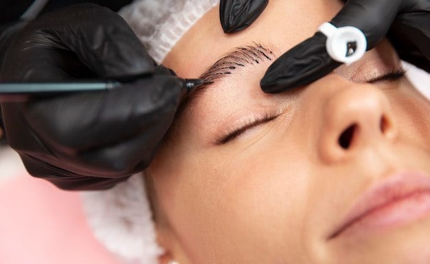 Técnico profesional realizando un procedimiento de microblading de cejas