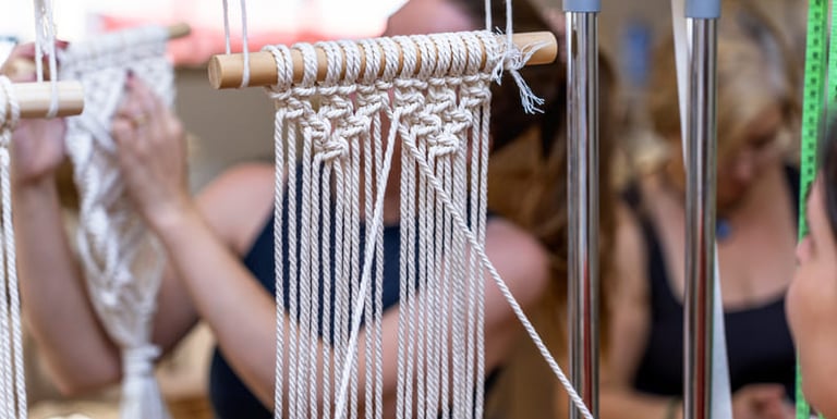 “Artesanos creando tapices de macramé hechos a mano con cuerda de algodón blanco en un taller