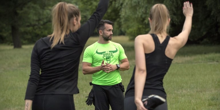 Trener stojący przed dwiema dziewczynami uprawiającymi stretching.
