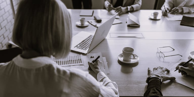 Femme assise à une table avec plusieurs personnes qui présente un projet commercial