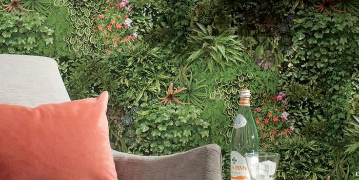 Modern living room featuring a vertical garden wall behind a grey armchair with an orange cushion.