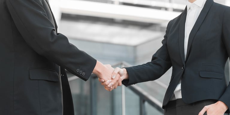 two men shaking hands in front of a building
