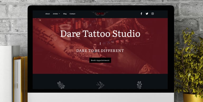 a computer screen on a desk showing the home page of a tattoo studio on the screen