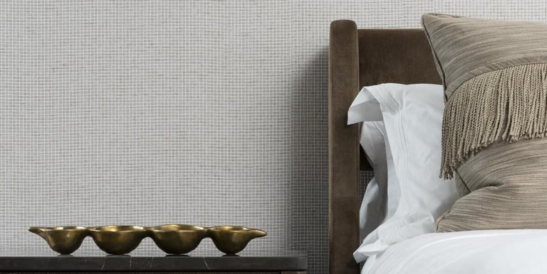 Luxury bedroom featuring textured light gray wallpaper, a brown velvet headboard, and elegant gold decor.